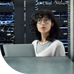 A person sitting in a datacenter environment behind a laptop.